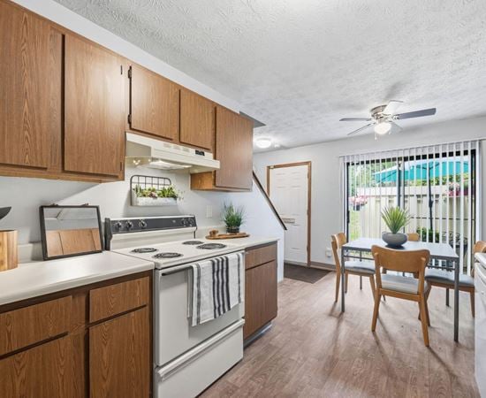 A kitchen with wooden cabinets and a white stove top oven.